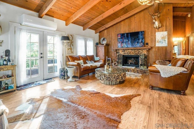 living room featuring a wall mounted AC, plenty of natural light, french doors, and wooden walls