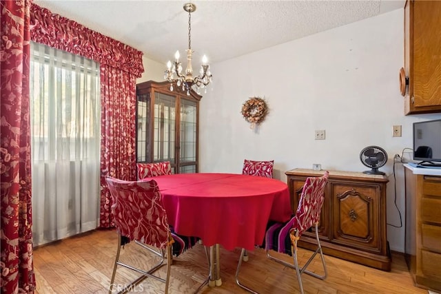 dining area with a textured ceiling, a chandelier, and light hardwood / wood-style floors