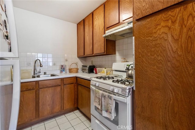 kitchen with sink, backsplash, light tile patterned flooring, and white gas stove