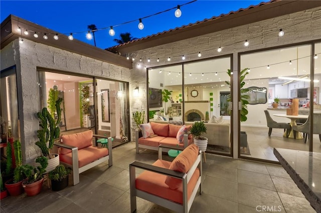 patio at night with an outdoor living space with a fireplace