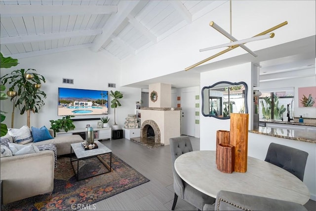 living room featuring wood ceiling, beam ceiling, an inviting chandelier, high vaulted ceiling, and a fireplace