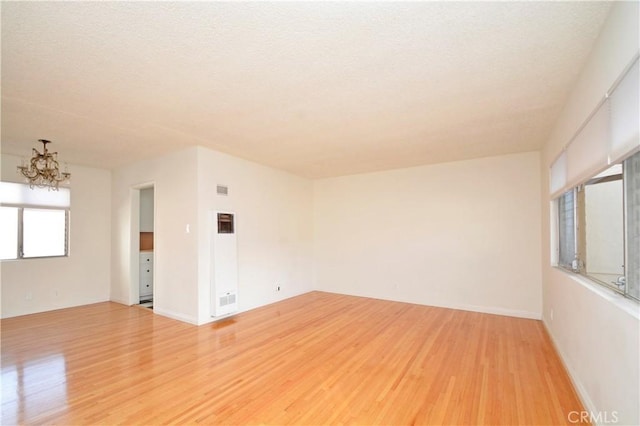 unfurnished room with a notable chandelier and light hardwood / wood-style flooring