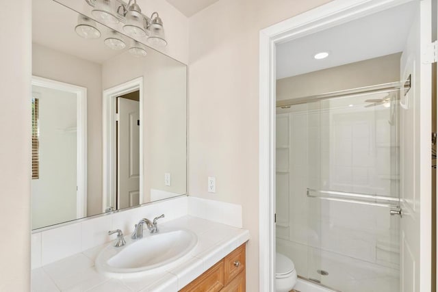 bathroom with toilet, vanity, and a shower with door