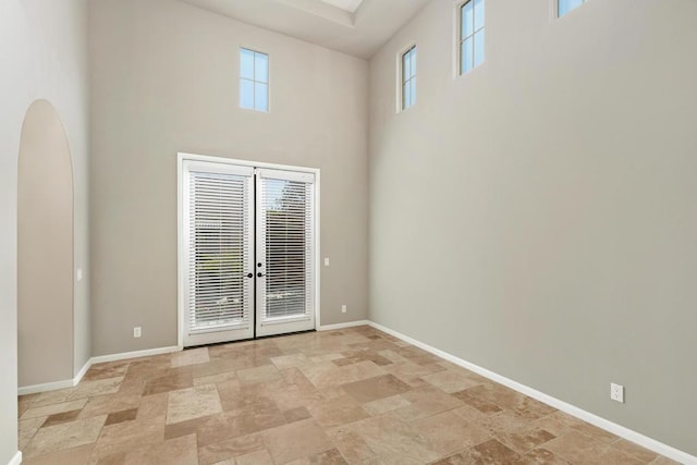 unfurnished room featuring french doors and a towering ceiling