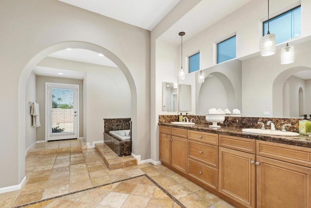 bathroom featuring tiled bath and vanity