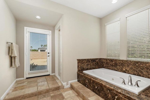 bathroom with tiled bath and a wealth of natural light