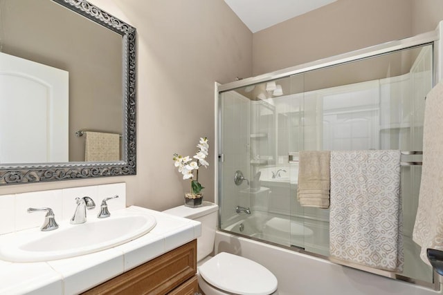 full bathroom with backsplash, bath / shower combo with glass door, toilet, and vanity