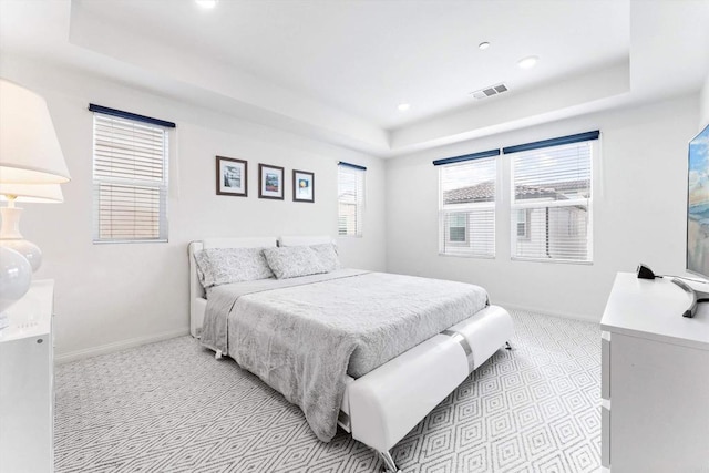 carpeted bedroom featuring a raised ceiling and multiple windows