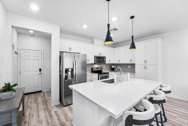 kitchen with sink, white cabinets, stainless steel appliances, and a kitchen island with sink