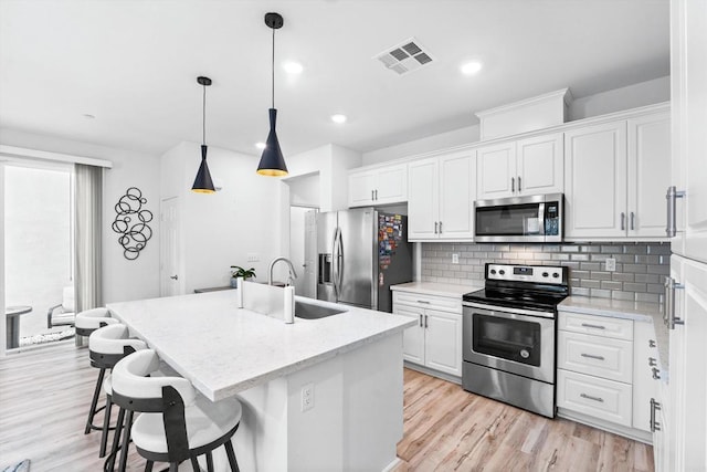 kitchen with white cabinetry, a center island with sink, and stainless steel appliances