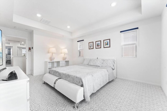 bedroom featuring a raised ceiling and light carpet