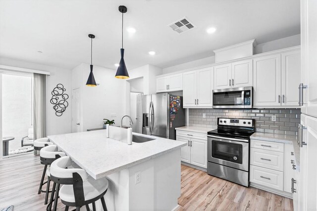 kitchen featuring white cabinetry, appliances with stainless steel finishes, and a kitchen island with sink