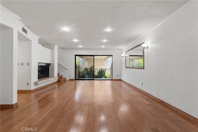 unfurnished living room with wood-type flooring, a wealth of natural light, and ornamental molding