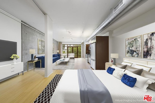 bedroom featuring light hardwood / wood-style flooring and stainless steel refrigerator