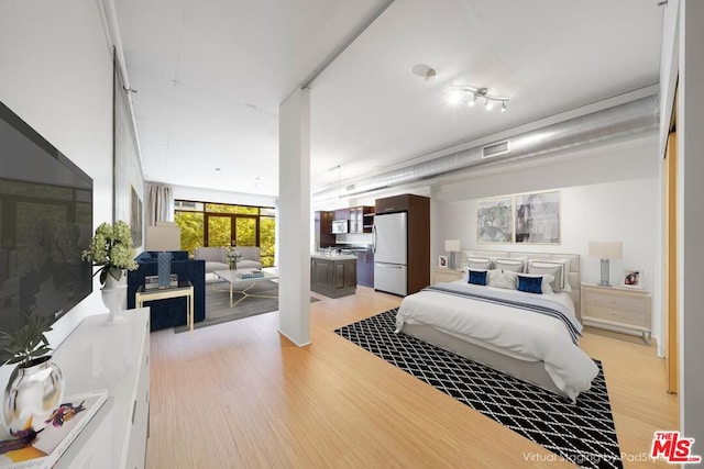 bedroom with light hardwood / wood-style floors and white refrigerator