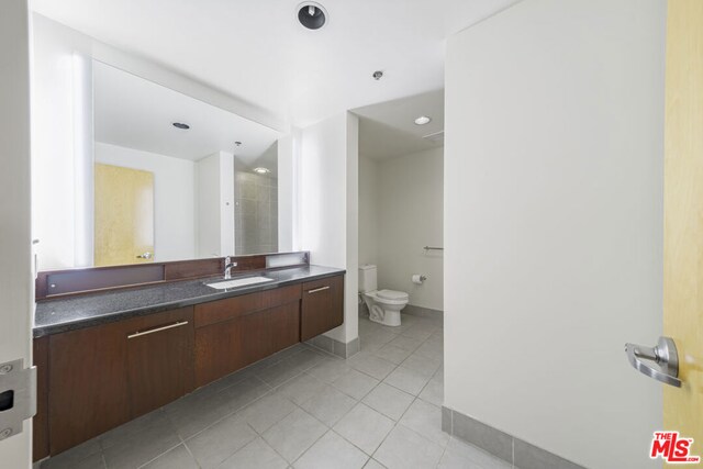 bathroom with toilet, vanity, and tile patterned flooring