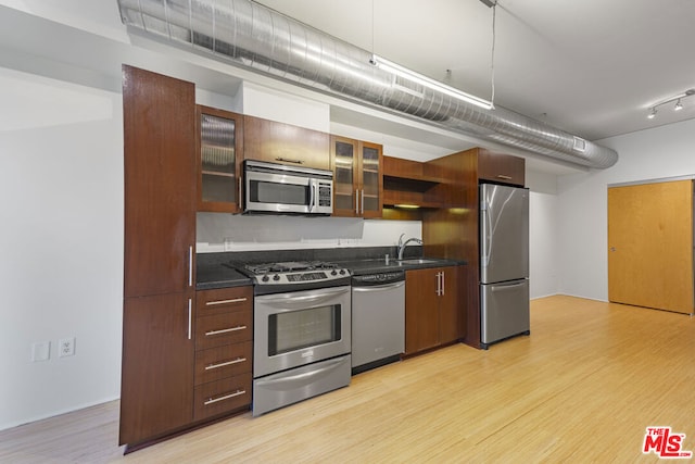 kitchen with stainless steel appliances, light hardwood / wood-style floors, and sink