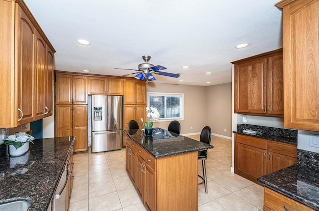 kitchen featuring light tile patterned floors, appliances with stainless steel finishes, dark stone counters, and a center island