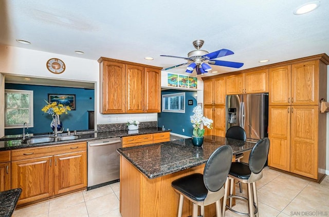 kitchen with ceiling fan, appliances with stainless steel finishes, sink, light tile patterned flooring, and a center island