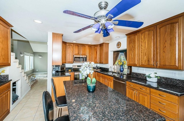 kitchen with ceiling fan, dark stone countertops, sink, light tile patterned flooring, and stainless steel appliances