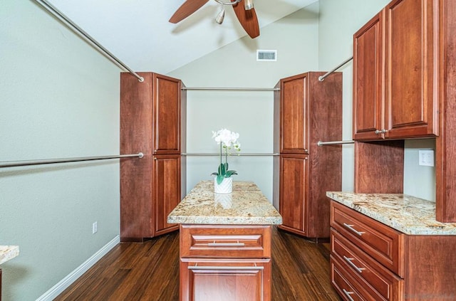 kitchen with ceiling fan, dark hardwood / wood-style flooring, lofted ceiling, light stone countertops, and a center island