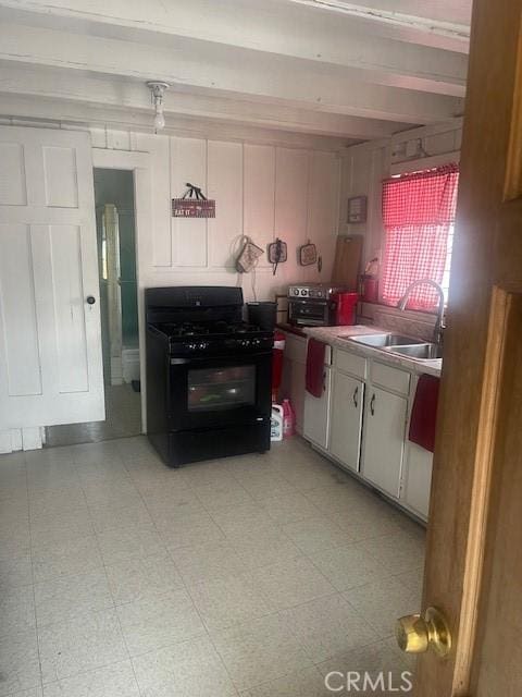 kitchen featuring beam ceiling, white cabinets, sink, and black range with gas cooktop