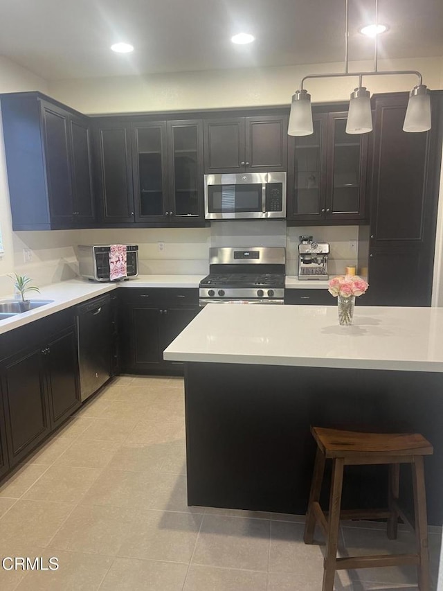 kitchen featuring appliances with stainless steel finishes, decorative light fixtures, light tile patterned floors, and sink