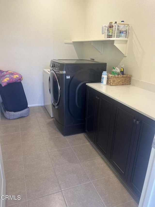 laundry area featuring washer and clothes dryer, cabinets, and light tile patterned floors