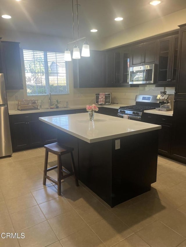 kitchen featuring a center island, sink, decorative light fixtures, light tile patterned flooring, and stainless steel appliances