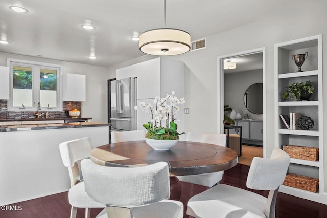 dining area with dark wood-type flooring, built in shelves, and sink