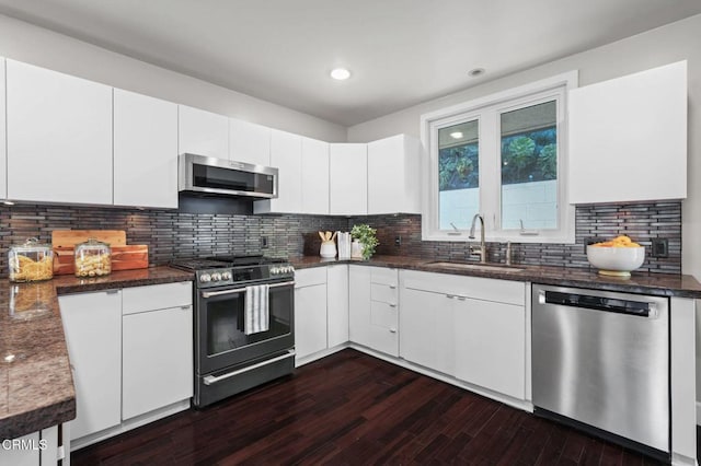 kitchen with tasteful backsplash, sink, appliances with stainless steel finishes, white cabinets, and dark hardwood / wood-style flooring