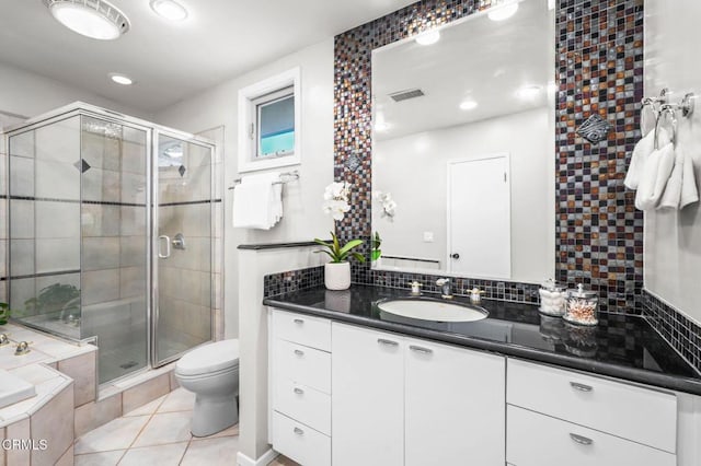 bathroom featuring toilet, decorative backsplash, tile patterned floors, walk in shower, and vanity