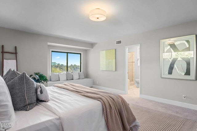 bedroom with light carpet and connected bathroom