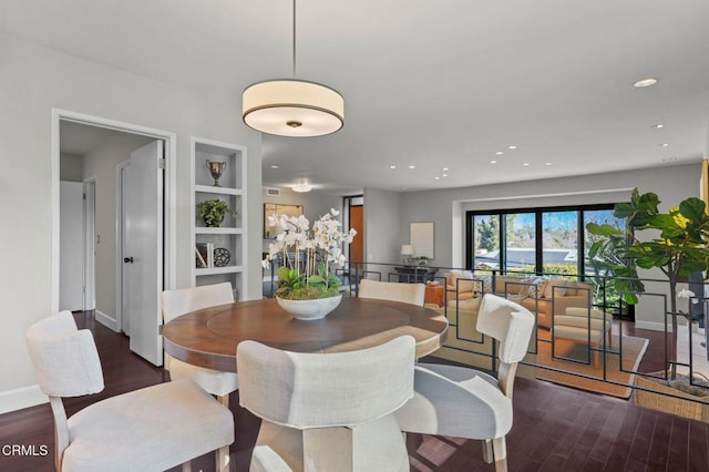 dining space with built in shelves and dark hardwood / wood-style flooring