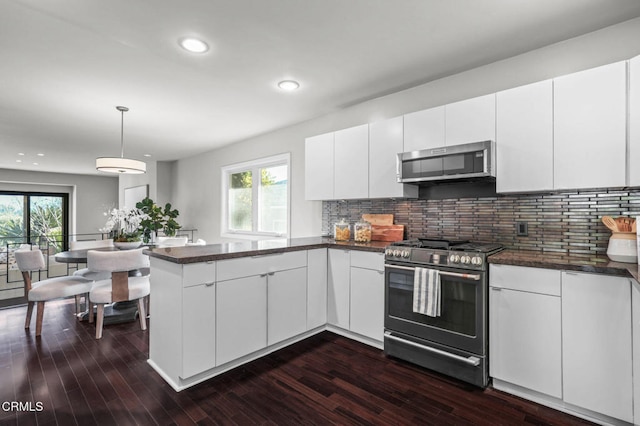 kitchen featuring pendant lighting, appliances with stainless steel finishes, white cabinetry, backsplash, and kitchen peninsula