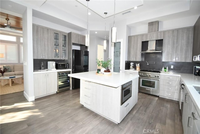 kitchen featuring wine cooler, backsplash, wall chimney range hood, high end range, and a kitchen island