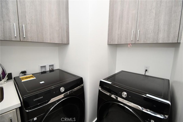 clothes washing area with cabinets and independent washer and dryer