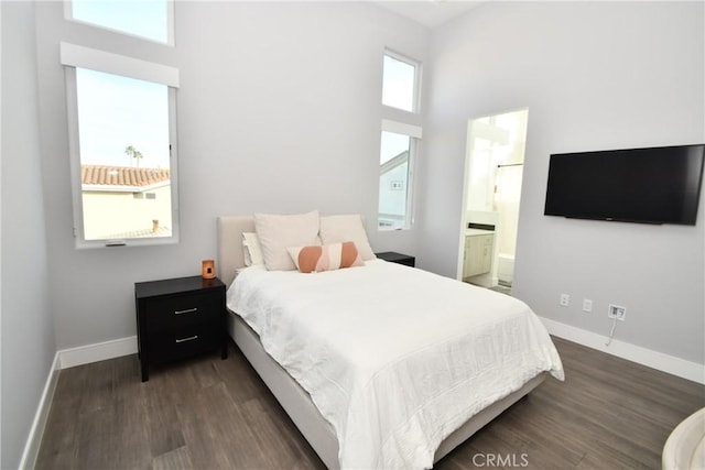 bedroom featuring dark hardwood / wood-style flooring, a high ceiling, and ensuite bath