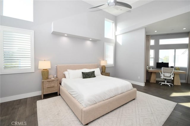 bedroom featuring ceiling fan, dark hardwood / wood-style floors, multiple windows, and built in desk