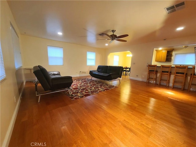 living area with baseboards, visible vents, ceiling fan, and light wood finished floors