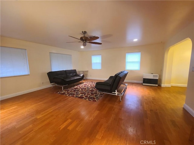 living room with arched walkways, ceiling fan, baseboards, and wood finished floors