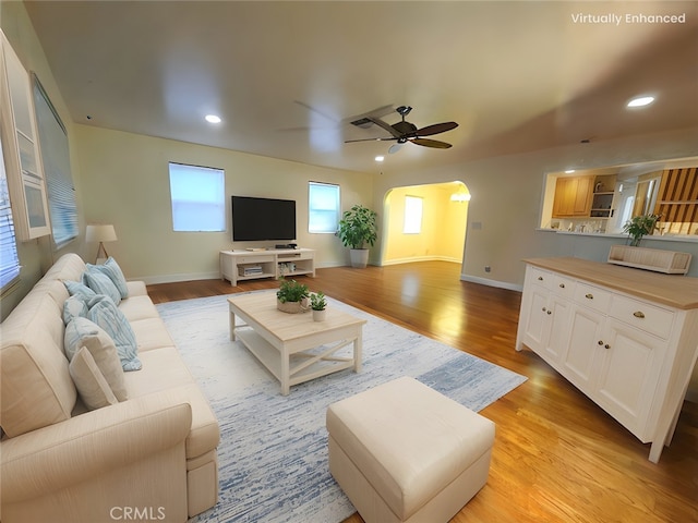 living room with arched walkways, light wood-style flooring, and recessed lighting