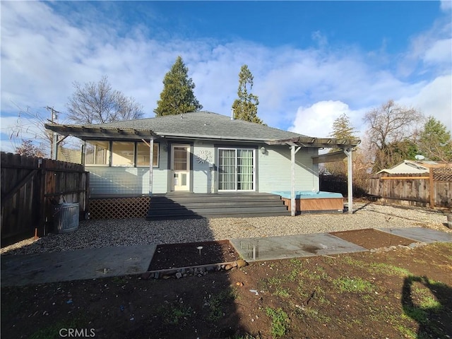 rear view of property featuring a patio area, a deck, a hot tub, and a pergola