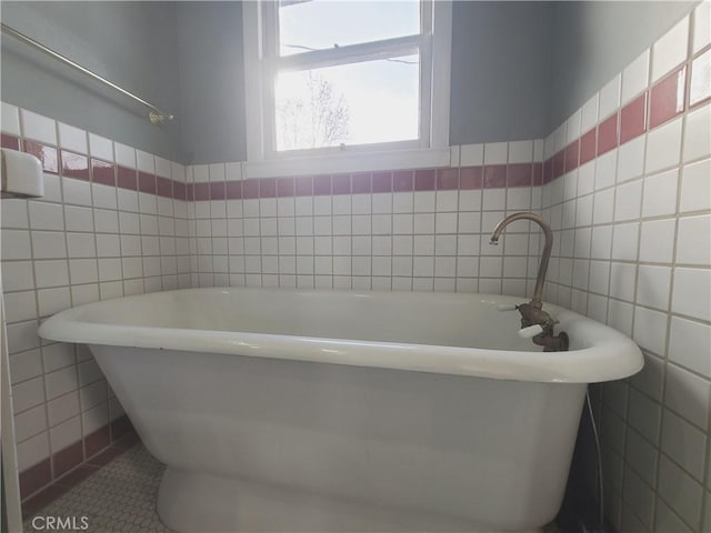 bathroom with a bath, tile patterned flooring, and tile walls