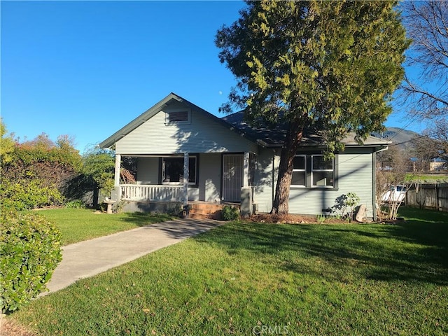 bungalow featuring covered porch and a front yard