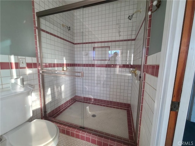 bathroom with toilet, tile patterned flooring, a shower with door, and tile walls