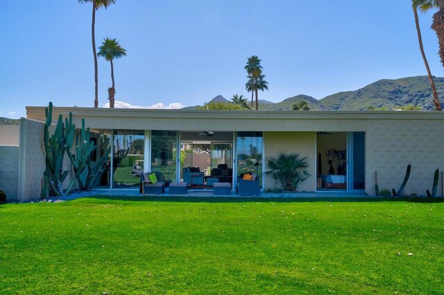 rear view of property with ceiling fan, a patio area, a lawn, a mountain view, and an outdoor hangout area