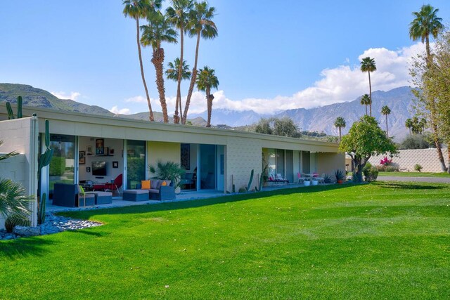 back of property with a mountain view, a patio area, a yard, and an outdoor living space