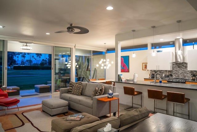 living room with ceiling fan with notable chandelier, sink, and expansive windows