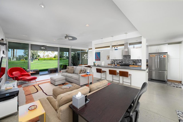 living room featuring ceiling fan and expansive windows